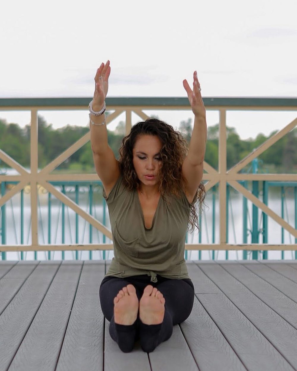Seated pose with arms raised overhead on an outdoor deck